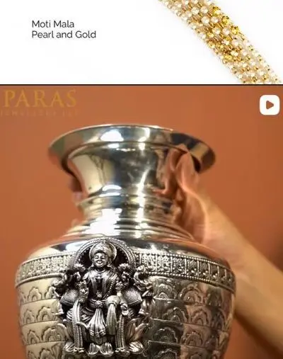 A silver kalash with Lakshmi in relief, held in two hands.