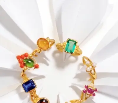 A circle of gold rings set with coloured stones on white petals.